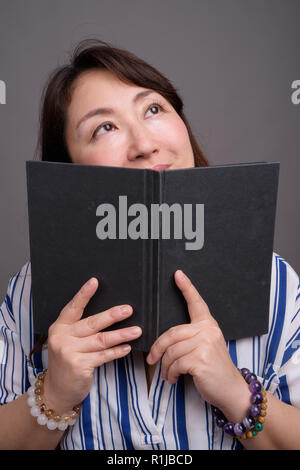 Portrait von Reifen schöne asiatische Geschäftsfrau lesen Buch Stockfoto
