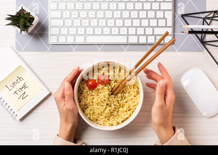 Aufnahme der Person, die Schüssel mit Nudeln und Stäbchen am Arbeitsplatz 7/8 Stockfoto