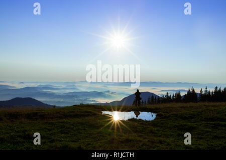Person ist fast am Horizont an der Stelle, an der Trennung von Erde und Wolken gegenüber der blaue Himmel und die Sonne direkt in die Stockfoto