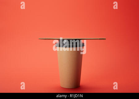 Stäbchen mit Papier Tasse Kaffee auf Rot, minimalistisches Konzept Stockfoto
