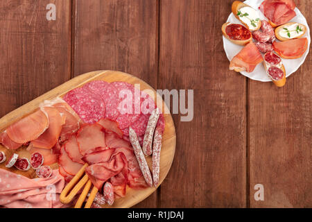 Wurstwaren. Ein Foto von verschiedenen Wurst und Schinken, Aufschnitt, Schuß von der Oberseite in einem dunklen rustikalen Hintergrund mit Kopie Raum Stockfoto