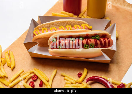 Nahaufnahme von Hot Dogs mit Pommes frites auf Papier auf weiße Oberfläche Stockfoto