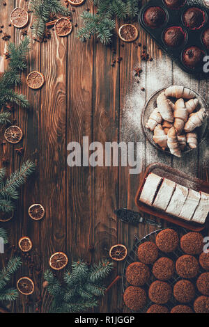 Blick von oben auf die leckeren gebackenen Plätzchen, Kekse und Muffins auf Holztisch, Weihnachten Konzept Stockfoto