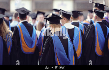 Die Absolventen an der Universität Abschlussfeier tragen mortarboard und Kleid Stockfoto