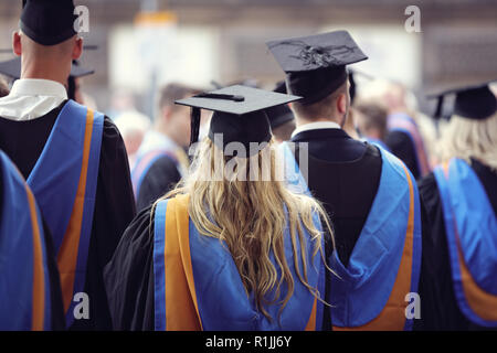 Die Absolventen an der Universität Abschlussfeier tragen mortarboard und Kleid Stockfoto