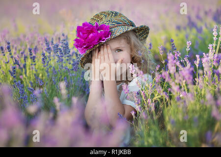 Junge schöne Mädchen zu Fuß auf der Lavendel Feld an einem Tag am Wochenende im wunderschönen Kleider und Hüte Stockfoto