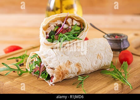 Tortilla Wraps mit Hähnchen und Gemüse auf Holz- Hintergrund. Chicken burrito. Gesundes Essen. Stockfoto