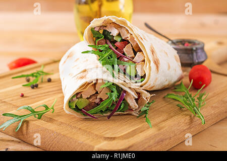 Tortilla Wraps mit Hähnchen und Gemüse auf Holz- Hintergrund. Chicken burrito. Gesundes Essen. Stockfoto
