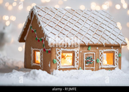 Lebkuchen-Haus im Schnee mit funkelnden silbernen hellen Hintergrund Stockfoto