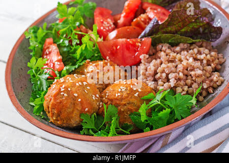 Frikadellen, Salat von Tomaten und Buchweizen Brei auf weissem Holztisch. Gesundes Essen. Diet Meal. Buddha Schüssel. Stockfoto