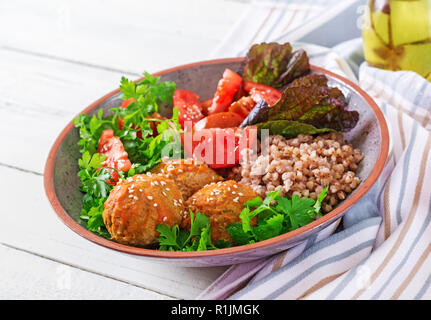 Frikadellen, Salat von Tomaten und Buchweizen Brei auf weissem Holztisch. Gesundes Essen. Diet Meal. Buddha Schüssel. Stockfoto