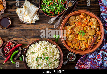 Traditionelle tajine Gerichte, Couscous und frischen Salat auf rustikalen Holztisch. Tajine Lamm Fleisch und Kürbis. Ansicht von oben. Flach Stockfoto