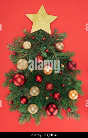 Blick von oben auf die Pine Tree Branches, Golden Star und Weihnachtskugeln in Weihnachtsbaum auf Rot isoliert angeordnet Stockfoto