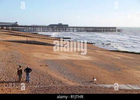 Hastings, East Sussex, UK. 11 Nov, 2018. UK Wetter: wunderschön sonnigen Start in den Tag in der Küstenstadt Hastings wie ein paar Leute Spaziergang entlang der Strandpromenade. Die Leute am Strand entlang mit einem Hund herum laufen. © Paul Lawrenson 2018, Foto: Paul Lawrenson/Alamy leben Nachrichten Stockfoto