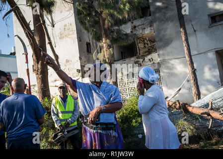 Aschkelon, Israel. 13 Nov, 2018. Die Israelischen Bürger prüfen Sie die Schäden im Gebäude, das von einer Rakete aus dem Gazastreifen letzte Nacht abgefeuert geschlagen wurde. Palästinensische militante fast 400 Raketen und Mörsergranaten aus dem Gazastreifen in Israel begann am Montag Nacht, Israelische Armee Sprecher Jonathan Conricus sagte. Credit: Ilia Yefimovich/dpa/Alamy leben Nachrichten Stockfoto