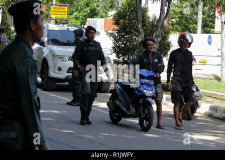 Lhokseumawe, Aceh, Indonesien. 13 Nov, 2018. Die islamische Scharia Polizeioffizier (Wilayatul Hisbah) gesehen stoppen ein Kraftfahrer einen Kurzschluß tragen während des routinemäßigen Razzien in Lhokseumawe. islamische Scharia Polizisten (Wilayatul Hisbah) bieten sarongs Für diejenigen, die die islamische Scharia durch Gewalt in der Stadt Lhokseumawe verletzt, Aceh ist die einzige Provinz in Indonesien mit der größten Bevölkerung von Muslimen in der Welt, der die islamische Scharia wie Ausschuss caning implementiert und die Durchführung von routinemäßigen Raids Für diejenigen, die Fest für Frauen und kurze Hosen für Männer gekleidet sind. (Credit Ima Stockfoto