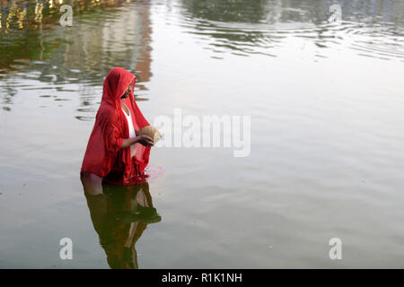 Kathmandu, Nepal. 13. November 2018. Eine Nepalesische devotee gesehen Gebete an die untergehende Sonne auf dem Wasser während der CHHATH Puja festival Chhath Festival, auch als Surya Pooja, oder Anbetung der Sonne bekannt, die in den Teilen von Indien und Nepal als Anhänger beobachtet wird, Hommage an die Sonne und das Wasser Götter. Credit: ZUMA Press, Inc./Alamy leben Nachrichten Stockfoto