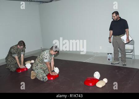 Alexander Pashos (rechts), Training Spezialist mit der Provost Marshal Office (PMO), Marine Corps Base Camp Pendleton (MCB), während beobachtet US Marine Corps Cpl. Ryan Swiecicki, Wachmann (links) und Pfc. Angel Sanchez, zusätzliche Sicherheitskräfte, sowohl mit PMO, MCB Camp Pendleton, Durchführung der Herz-Lungen-Wiederbelebung (HLW) auf einem simulierten Unfall während einer Erste Hilfe und HLW-Klasse im MCB Camp Pendleton, Kalifornien, Oktober 9, 2018. Die Marines an der Klasse beigebracht, lebensrettende Techniken, die eine Heimlich Manöver Demonstration, Bandagieren und Gliedmaßen Schiene applicatio enthalten Stockfoto