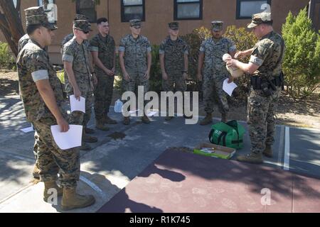 Us Marine Corps Cpl. Matthäus Roach (rechts), Militär, Polizei, Offizier mit der Provost Marshal Office (PMO), Marine Corps Base (MCB), Camp Pendleton, demonstriert das Heimlich Manöver auf ein Kind training Simulation Puppe zu anderen Marines mit PMO während eines Erste Hilfe und Herz-Lungen-Wiederbelebung Klasse im MCB Camp Pendleton, Kalifornien, Oktober 9, 2018. Die Marines an der Klasse beigebracht, lebensrettende Techniken, die eine Heimlich Manöver Demonstration, Bandagieren und Gliedmaßen Schiene Anwendung und den Funktionen eines Automatischen Externen Defibrillators enthalten. Stockfoto