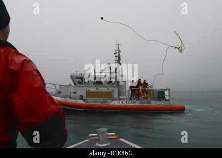 Coast Guard Petty Officer 3. Klasse Alex Sheltra bereitet eine wurfleine von einem 45-Fuß-Antwort Boat-Medium Crew im Hafen von Valdez, Alaska, Okt. 10, 2018 zu erhalten. Die Station Valdez Besatzungen durchgeführten Schulungen, inklusive Suchmuster und Schiff abschleppen. Stockfoto