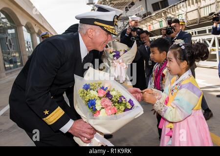 Insel Jeju, Republik Korea, (Okt. 2010) 12, 2018), Konteradmiral. Karl Thomas, Commander, Kampf Kraft 7. Flotte, Task Force 70, Carrier Strike Group 5, Austausch Geschenke mit einem jungen Mädchen Pier in der Republik Korea (ROK) Marine Basis in Jeju. Thomas Befehle die USS Ronald Reagan (CVN 76) Carrier Strike Group, die sich auf die US-Flotte 7 Bereich der Vorgänge ist zur Unterstützung der Sicherheit und Stabilität in der Region Into-Pacific eingesetzt. Stockfoto