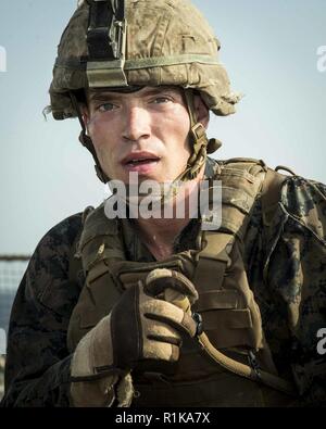 Arabischen Golf - US Marine Sgt. John Horn, eine Infanterie Truppführer mit Kilo Firma, Bataillon Landung Team 3/1, 13 Marine Expeditionary Unit (MEU), Pausen zum Ausruhen und Wasser trinken während der kriegerischen künste Instructor Kurs Höhepunkt an Bord der Whidbey Island-Klasse dock Landung Schiff USS Rushmore (LSD 47), Okt. 11, 2018. Das Essex Amphibious Ready Gruppe und dem 13 MEU sind in die USA 5 Flotte Bereich der Maßnahmen zur Unterstützung der Marine im Einsatz für die Stabilität und Sicherheit in der Region zu gewährleisten und verbindet das Mittelmeer und den Pazifischen Raum durch den westlichen Ind Stockfoto