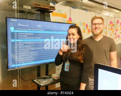 Staff Sgt. Kassandra Johnson, 2. System Operations Squadron NCO verantwortlich, das Routing von Daten Team, und Markus Ducommun, ein Ingenieur, posieren für ein Foto mit der App, Home, an die Zentralen Labore Büro in Chicago, Illinois, 5. Oktober 2018. Cyber Flieger von der 557th Wetter Flügel arbeiten mit innovativen Unternehmen, Software, die Effizienz für die Luftwaffe zu erhöhen entwickeln können. () Stockfoto