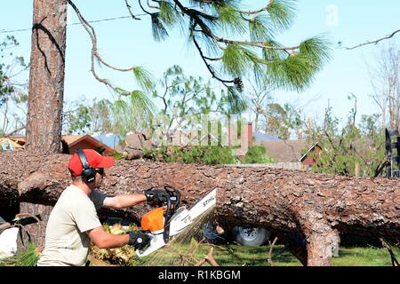 Staff Sgt. Alex Spano, elektrische Facharbeiter aus der 202. Geben Sie der Camp Blanding, Fla., verwendet eine Kettensäge zu helfen, einen gefallenen Baum sperren einer Wohnstraße in Eschwege, Fla., Okt. 13, 2018 klar. Hurricane Michael links schwere Schäden im gesamten Panama City Bereich, und die 202 war auf für ihre Sachkenntnis in Route clearing genannt. Stockfoto