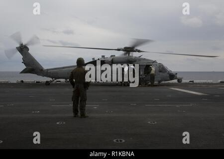 Marines mit Amphibious Reconnaissance Platoon ein U.S. Navy MH-60S Seahawk Hubschrauber auf dem Flugdeck, die Ladung des 31 Marine Expeditionary Unit während Helocast und spezielle Patrol Insertion und Extraktion der Ausbildung an Bord der Amphibisches Schiff USS Wasp (LL 1), unterwegs in der East China Sea, Okt. 14, 2018. Helocasting und SPIE ermöglichen die Recon Marines zu betreten und zu verlassen taktische Landung Zonen, die mit Hubschraubern bei amphibischen Operationen nicht zugänglich sind. Die 31. MEU, das Marine Corps' nur kontinuierlich vorwärts - bereitgestellt MEU, bietet eine flexible Kraft bereit, ein Wi durchführen Stockfoto