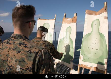 2. Lt. Maxwell Bennett, ein Kommunikation Strategie und Operations Officer mit 31 Marine Expeditionary Unit stellt sein Ziel während der Pistole Qualifikation an Bord der Flight Deck der Amphibisches Schiff USS Wasp (LL 1), unterwegs in der East China Sea, Okt. 15, 2018. Bennett, ein Eingeborener von Stilwell, Kansas, graduiert von William Jewell College im Mai 2016; er im November 2016 in Betrieb genommen. Marines durchlaufen jährlich Gewehr und Pistole Qualifikationen in ihre waffenfertigkeiten und Handhabung vertraut zu bleiben. Die 31. MEU, das Marine Corps' nur kontinuierlich vorwärts - bereitgestellt MEU, bietet eine f Stockfoto