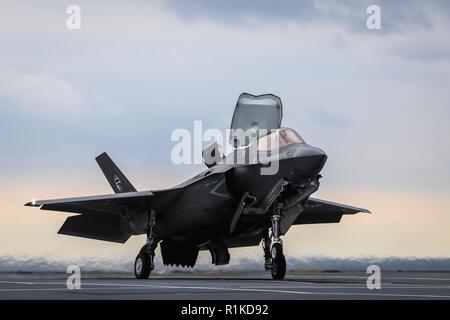 Die erste an Bord befindliche Rolling vertikale Landung (SRVL) wurde mit einer F-35B Blitz II Joint Strike Fighter jet Studien Durchführung an Bord der neue britische Flugzeugträger HMS Queen Elizabeth durchgeführt. Großbritannien ist das einzige Land plant derzeit die Manöver zu verwenden, welche die Jets onboard mit schwerer Lasten, was bedeutet, dass sie nicht brauchen teuren Kraftstoff und Waffen über Bord zu werfen, jetzt, vor der Landung zu landen. Die heutige Landung, von Peter Wilson, ein BAE Systems UK Test Pilot mit der F-35 Pax River integrierten Test Kraft geleitet wurde, fand um genau 10:30 Uhr Oktober 13, 2018, aus dem Osten coa Stockfoto