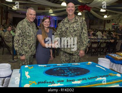 CAMP LEMONNIER, Dschibuti - Camp Lemonnier kommandierenden Offizier, Marine Kapitän Charles J. DeGilio (Links), stellt für einen Kuchen schneiden durch den ältesten und jüngsten Segler in die Teilnahme an einer Marine Ball, 63-jährige Kapitän Timothy S. Roush und 21-jährige Master-at-Arms 3. Klasse Genevieve Boucher, Feiern im Geburtstag der U.S. Navy auf der Basis der VZ-Anlage, Okt. 13, 2018. Am 13. Oktober 1775, die Marine wurde durch eine Entschließung des Continental Congress gegründet. Das Thema der diesjährigen Feier wird vom Meer geschmiedet. Stockfoto