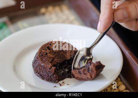 Der Mann ißt, heiße Schokolade Kuchen souffle auf weiße Platte. Stockfoto