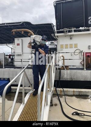 Der Küstenwache Donald Horsley crewmember hilft einem beschlagnahmten Kokains Sendung in San Juan, Puerto Rico Offload, nach dem Verbot der Drogenschmuggel - schnelles Boot Okt. 13, 2018 off Luquillo, Puerto Rico. Der Donald Horsley Crew und die Reaktion der US-Zoll- und Grenzschutzbehörde und Immigration und Zoll Enforcement-Homeland Sicherheit Untersuchungen Einheiten 2.324 Pfund Kokain in diesem Fall mit einem geschätzten Großhandel Wert von $ 30 Mio. beschlagnahmt. Stockfoto