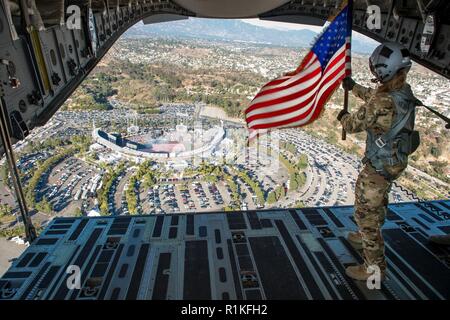 Staff Sgt. Kori Myers, 418 Flight Test Squadron last Master, Wellen, die die amerikanische Flagge aus der Rückseite des C-17 Globemaster III während der Anfang von Spiel 3 der National League Championship Series zwischen den L.A. Schwindler und Milwaukee Brewers, Okt. 15, 2018. Der 412 Test Wing auf der Edwards Air Force Base, Kalifornien, sofern die C-17 Für die feierliche Überführung. Stockfoto