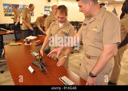 DAHLGREN, Va (Okt. 2010) 12, 2018) - Cmdr. Steven Perchalski, rechts, und Leutnant Adam Mattison untersuchen einen Weltkrieg I bombsight - dient der Prüfung an den Dahlgren Naval Proving Ground in den 1920er zu führen er und 1930er Jahre - während einer Feier im Geburtstag der Marine gehalten an der Naval Surface Warfare Center Dahlgren Division (NSWCDD). Das Flugzeug Kurs - Einstellung bombsight ist eines der wenigen erhaltenen Beispiele der vielen bombsights bei Dahlgren getestet. NSWCDD feiert 100 Jahre zukunftsweisende technologische Innovation im Dienste der warfighter in einem hundertjährigen Grand finale Veranstaltung Okt. 19, gehören Stockfoto