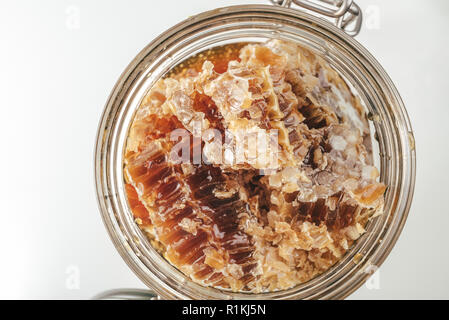 Stücke von Bienenwaben in eine Schüssel geben. Frische Biene Honig in honeycomb Stücke auf weißem Hintergrund. Stockfoto