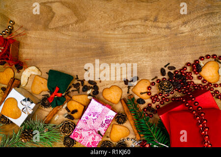 Weihnachten Hintergrund mit Cookies, Geschenke, Tannenzweigen und Gewürzen auf den alten grunge Holzbrett, kopieren Raum Stockfoto