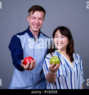 Multi-ethnische Vielfalt Paar im Studio mit grünen und roten Apfel Obst Stockfoto