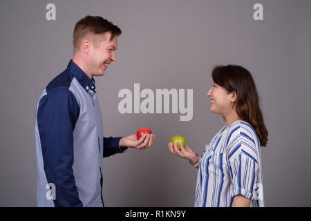 Multi-ethnische Vielfalt Paar im Studio mit grünen und roten Apfel Obst Stockfoto