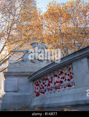 Machine gunner auf einem Kriegerdenkmal mit gestrickten Mohnblumen rund um die Gedenkstätte gewickelt Stockfoto