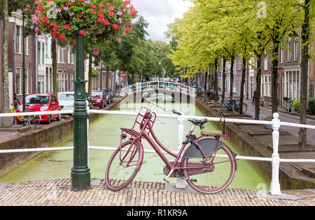 Blick auf die Stadt Delft in den Niederlanden mit Wasser, Kanal und Vintage Fahrrad auf der Brücke im Sommer Stockfoto