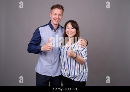 Geschäftsmann und Ausgereiften asiatischen Geschäftsfrau Holding Big Orange Slice Stockfoto