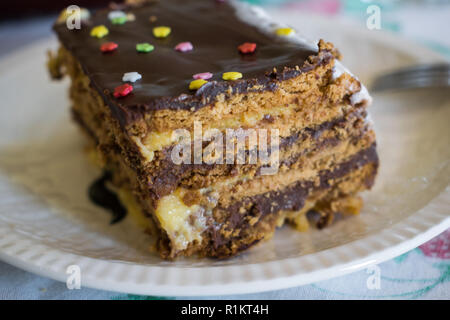 Teil des Kuchens mit Keksen, Schokolade und Vanille dekoriert mit bunten Streuseln. Selektiver Fokus Stockfoto