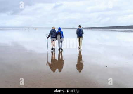 Familie von drei zu Fuß am Strand bei Ebbe an Westward Ho!, Devon, Großbritannien, an einem bewölkten und bewölkten Tag im Sommer Stockfoto