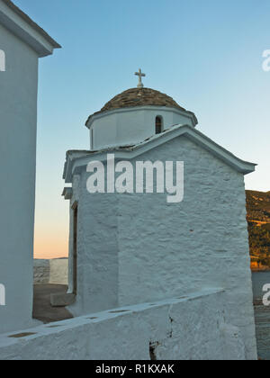 Kleine Kirche im Sonnenuntergang auf einer Klippe oberhalb von Bucht und Hafen von Skopelos, Insel Skopelos in Griechenland Stockfoto