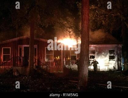 Georgien Army National Guard Sgt. Blake Mote der Calhoun, GA-basierte 190 Military Police Company aus einem brennenden Haus, nachdem sie von Lieutenant Michael Smith der Donalsonville Feuerwehr- und Rettungsdienste Abteilung entlastet werden. Mote, ein Feuerwehrmann und erweiterte Emergency Management Techniker mit dem Clayton County Fire und Emergency Management Services, war auf Patrouille mit seiner Einheit und Rettungskräfte, als sie darauf aufmerksam gemacht wurden, um das Feuer zu reagieren. ( Stockfoto