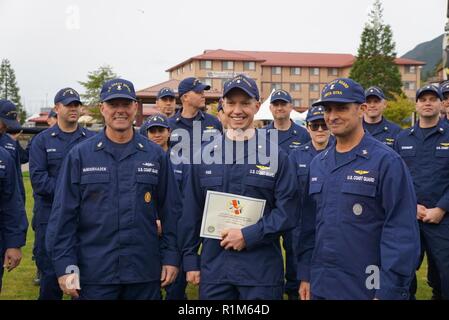 Master Chief Petty Officer der Coast Guard Jason M. Vanderhaden präsentiert Petty Officer 3rd Class Phillip Ping mit der Air Station Sitka Soldaten des Quartals Award bei Air Station Sitka, Alaska, Okt. 18, 2018. Die air Station stellt diese Auszeichnung zu einer Einheit, die außergewöhnliche und hervorragende Leistung der Aufgabe zeigt. Stockfoto