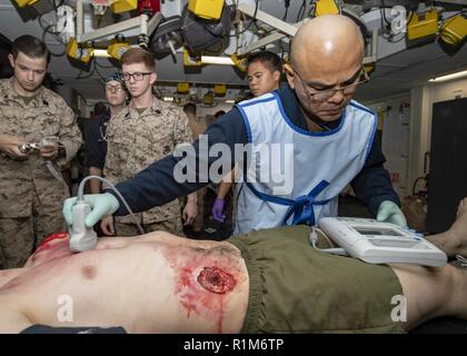 ARABIAN GULF (Okt. 2010) 11, 2018) Hospital Corpsman 2. Klasse Marcelo Castellon nimmt Ultraschallbilder von simulierten Verletzungen bei einem Unfall bohren an Bord der Wasp-Klasse amphibisches Schiff USS Essex (LHD2) während der regelmäßigen Bereitstellung mit der Essex Amphibious Ready Group (ARG) und 13th Marine Expeditionary Unit (MEU). Essex ist eine tödliche, flexibel, und anhaltende Navy-Marine Corps Team in die USA 5 Flotte Bereich der Maßnahme zur Unterstützung der Marine im Einsatz für die Stabilität und Sicherheit in der Region zu gewährleisten und verbindet das Mittelmeer und den Pazifischen thr Stockfoto