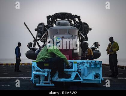 ARABIAN GULF (Okt. 2010) 11, 2018) der Luftfahrt Bootsmann Mate (Handling) 3. Klasse Jesse Prince betreibt ein Zugfahrzeug beim Verschieben einer CH-53E Sea Stallion Hubschrauber, zu der "Elche" der Marine Medium Tiltrotor Squadron (VMM) 166 (Verstärkt) beigefügt, in dem Hangar Bucht von der WASP-Klasse amphibisches Schiff USS Essex (LHD2) während der regelmäßigen Bereitstellung mit der Essex Amphibious Ready Group (ARG) und 13th Marine Expeditionary Unit (MEU). Essex ist eine tödliche, flexibel, und anhaltende Navy-Marine Corps Team in die USA 5 Flotte Bereich der Maßnahme zur Unterstützung der Marineoperationen bereitgestellt Stockfoto